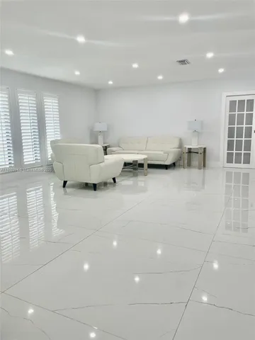a living room with chairs and kitchen view