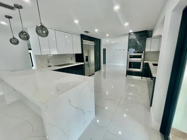 a view of a refrigerator in kitchen and an empty room