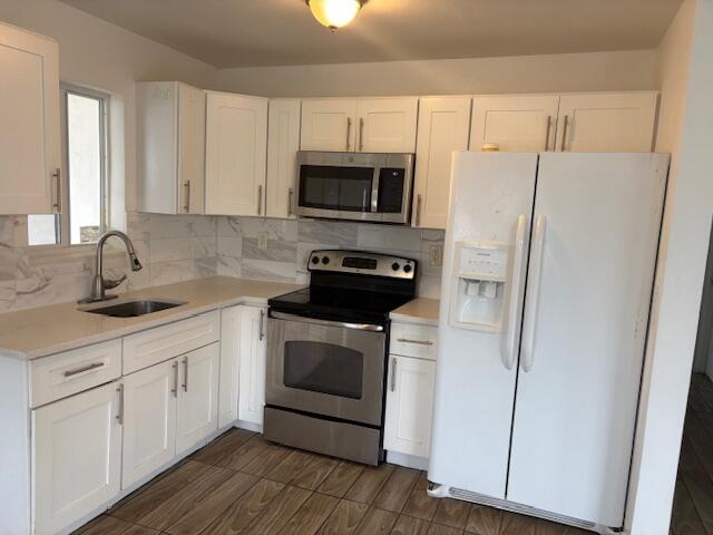 958 West 3rd Street Riviera Beach, FL 33404 - Photo 4 of 10 a kitchen with white cabinets stainless steel appliances and sink