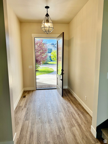 496 North Farmhouse Way, Unit 11 Midway, UT 84049 - Photo 13 of 50 Inviting entryway featuring wood-finish flooring, a geometric pendant light fixture, and a dark-paneled front door with matte black hardware