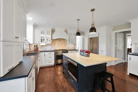 a kitchen with stainless steel appliances kitchen island granite countertop a stove a sink dishwasher and a cabinets with wooden floor