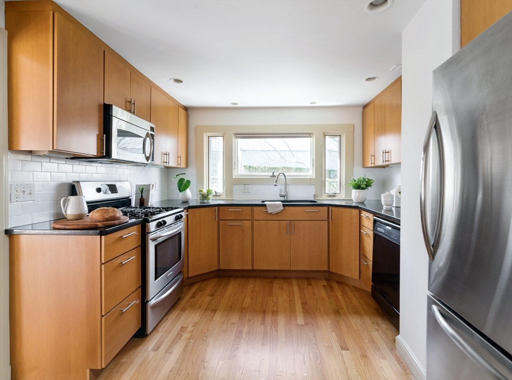 18 Kenilworth Road Arlington, MA 02476 - Photo 5 of 26 a kitchen with stainless steel appliances granite countertop a refrigerator a sink dishwasher a stove with wooden floors and cabinets