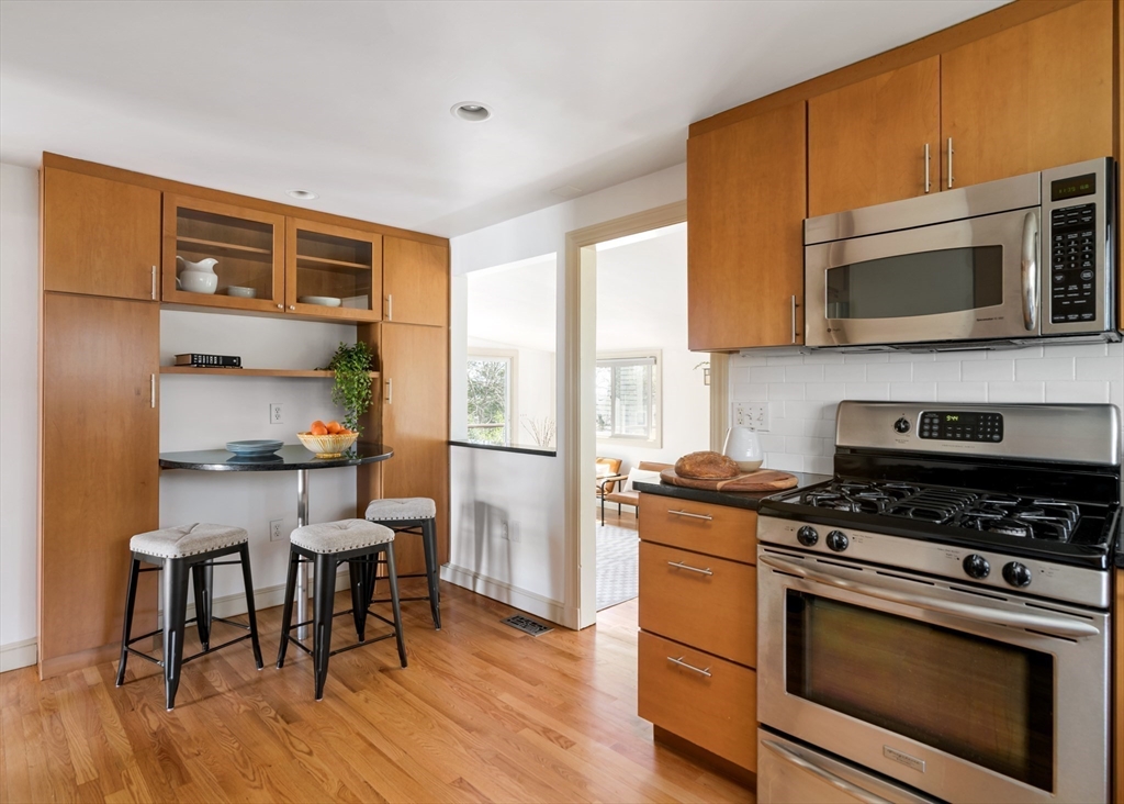18 Kenilworth Road Arlington, MA 02476 - Photo 6 of 26 a kitchen with stainless steel appliances a stove a microwave and wooden floors