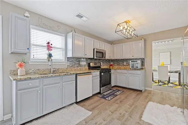 a kitchen with granite countertop a stove a sink dishwasher and a refrigerator