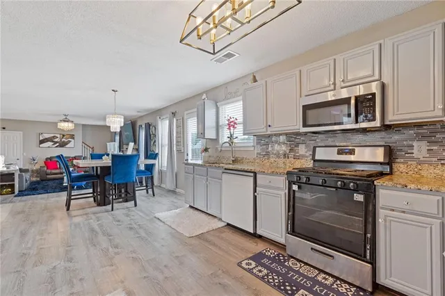 a kitchen with granite countertop a stove a sink and a microwave