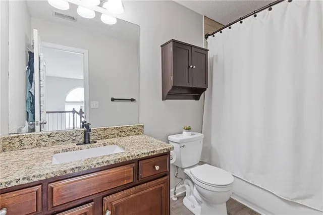 a bathroom with a granite countertop sink a toilet and a mirror