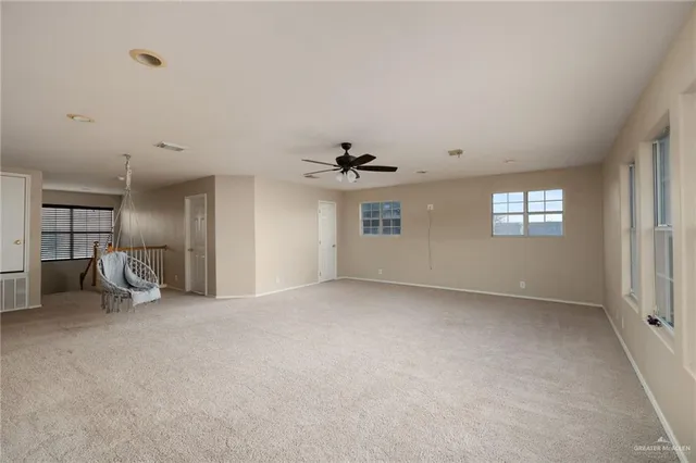 an empty room with windows and ceiling fan