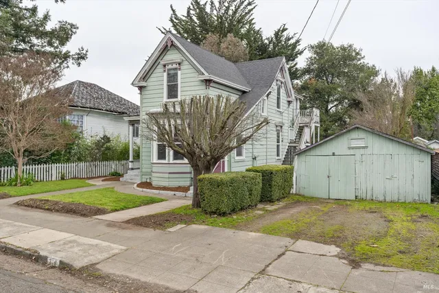 a view of a big house with a big yard and large trees
