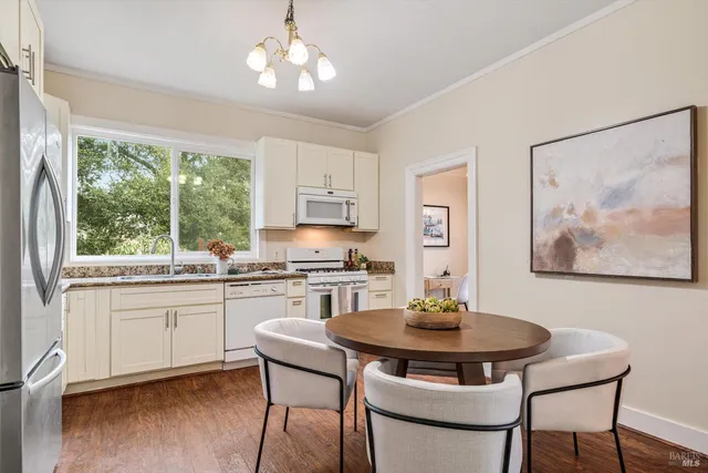 a kitchen with stainless steel appliances a dining table a stove and a refrigerator with wooden floor