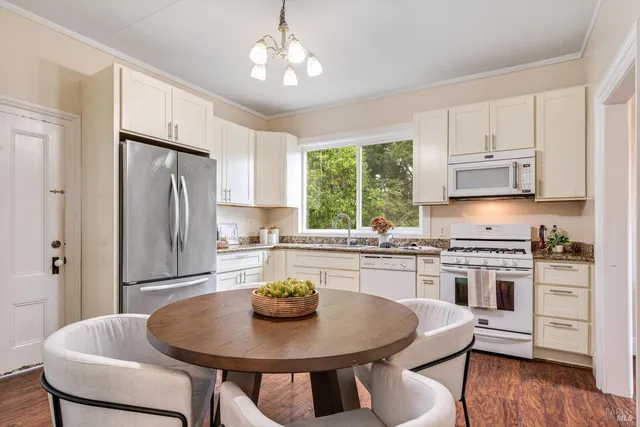 a kitchen with stainless steel appliances granite countertop a stove a refrigerator a sink a stove a dining table and chairs