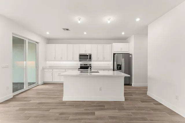 a view of kitchen with stainless steel appliances refrigerator sink and stove