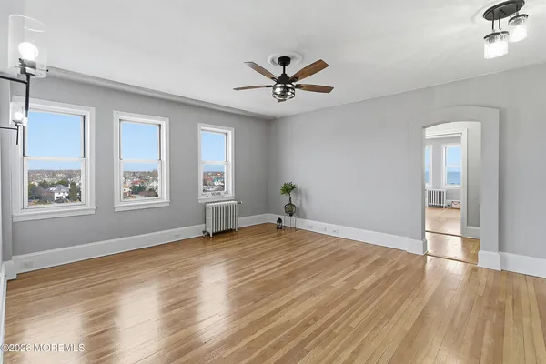 a view of empty room with wooden floor and fan