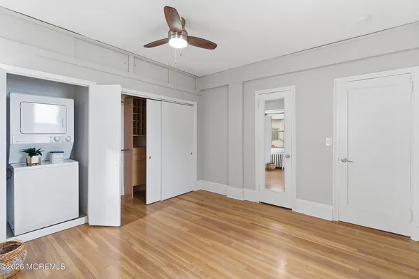 a view of empty room with wooden floor and ceiling fan