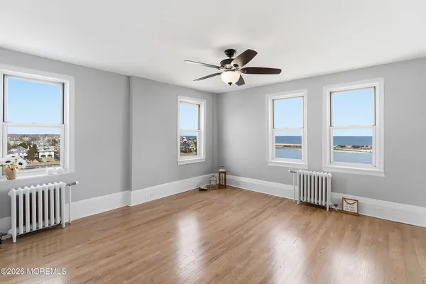 a view of an empty room with a window and wooden floor
