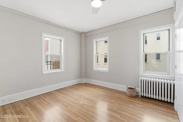 a view of empty room with wooden floor and fan