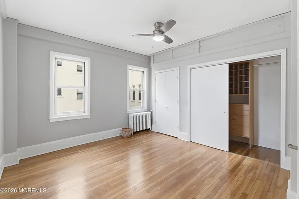 a view of an empty room with window and wooden floor
