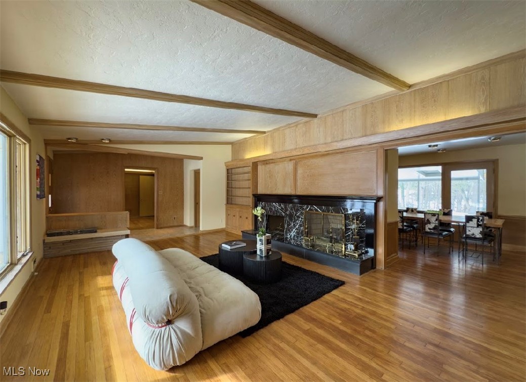 7817 Montello Road Independence, OH 44131 - Photo 4 of 35 Living room featuring beamed ceiling, a premium fireplace, hardwood / wood-style floors, and a textured ceiling