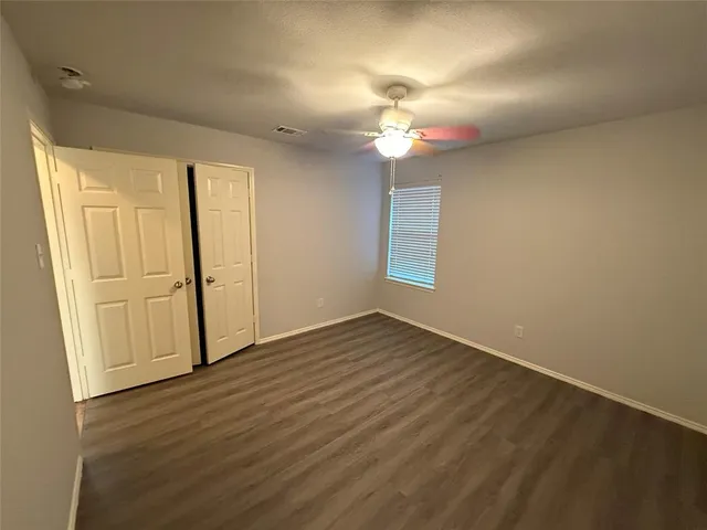 an empty room with wooden floor chandelier fan and windows
