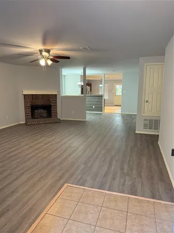 a view of a livingroom with a fireplace a ceiling fan and wooden floor