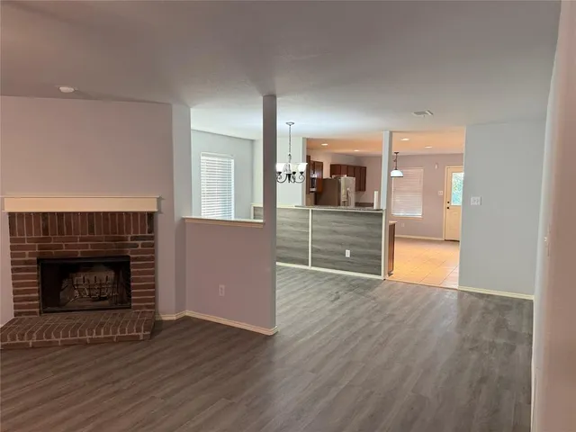 a view of a kitchen and an empty room with wooden floor and a fireplace