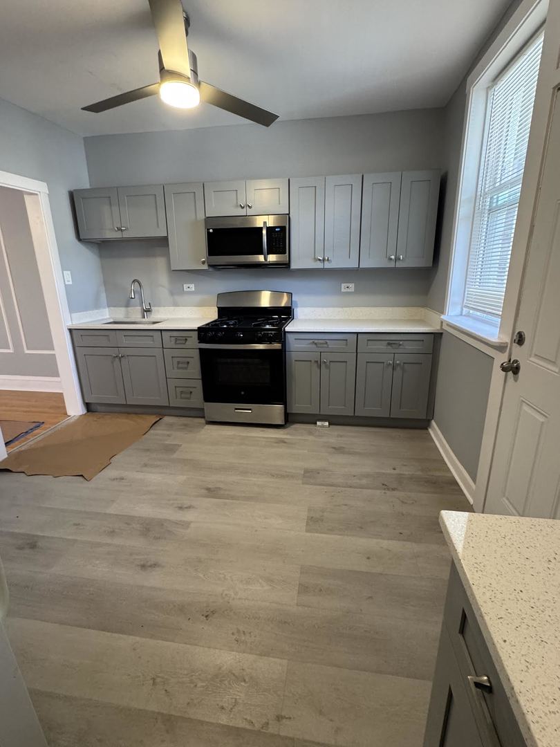 6231 North Francisco Avenue, Unit 2S Chicago, IL 60659 - Photo 21 of 24 a kitchen with stainless steel appliances a stove a sink a microwave a refrigerator and cabinets