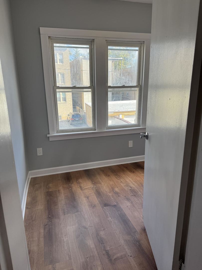 6231 North Francisco Avenue, Unit 2S Chicago, IL 60659 - Photo 9 of 24 an empty room with wooden floor and windows