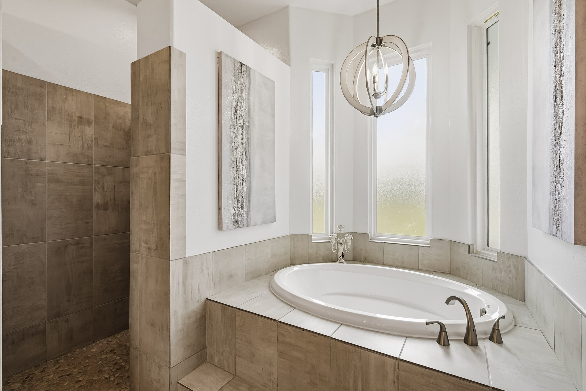3103 Brundrett Road Wallis, TX 77485 - Photo 21 of 45 Wash away the stress of the day in this spa-inspired walk-in shower, beautifully appointed with natural river rock flooring underfoot and dual shower heads for a luxurious bathing experience. Nearby, the elevated soaking tub serves as a peaceful retreat of its own, bathed in soft natural light streaming through three elongated privacy-glass windows. Together, these thoughtfully designed features create a serene sanctuary where relaxation comes naturally.