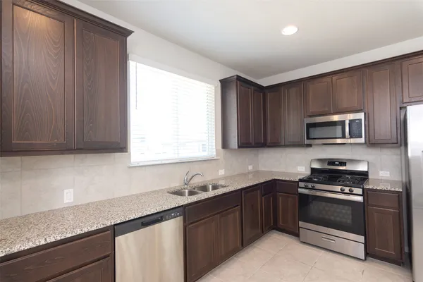 a kitchen with stainless steel appliances granite countertop a sink dishwasher a stove and a microwave oven with cabinets