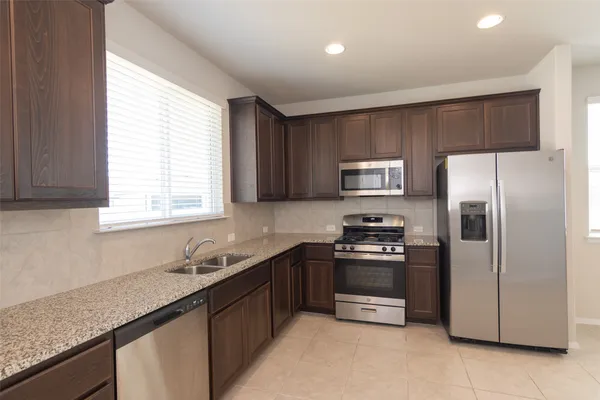 a kitchen with stainless steel appliances granite countertop a sink stove and refrigerator