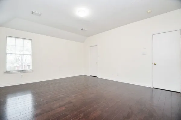 an empty room with wooden floor and window