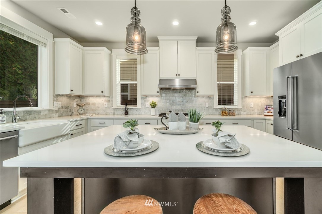 3318 238th Place Southeast Bothell, WA 98021 - Photo 11 of 36 a kitchen with stainless steel appliances kitchen island granite countertop a dining table and chairs