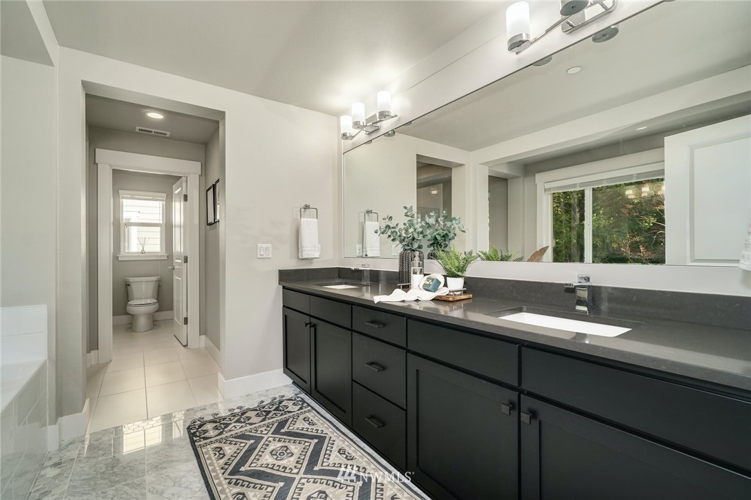 3318 238th Place Southeast Bothell, WA 98021 - Photo 23 of 36 a bathroom with a granite countertop sink a mirror and a shower