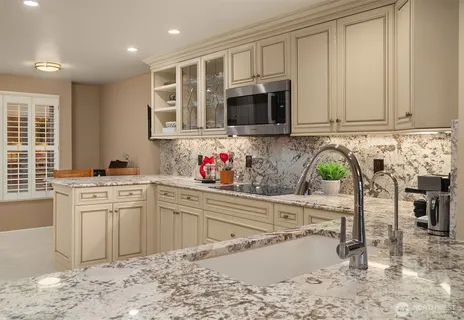 a kitchen with stainless steel appliances granite countertop a stove a sink and a microwave