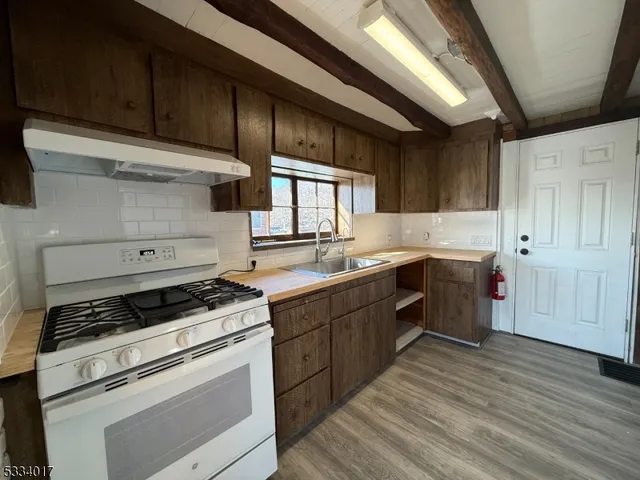 a kitchen with a stove white cabinets and wooden floor