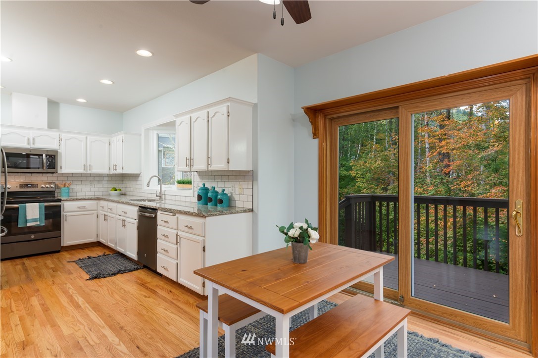 1220 Southwest 12th Street North Bend, WA 98045 - Photo 6 of 25 a kitchen with stainless steel appliances granite countertop a refrigerator a sink dishwasher and white cabinets with wooden floor