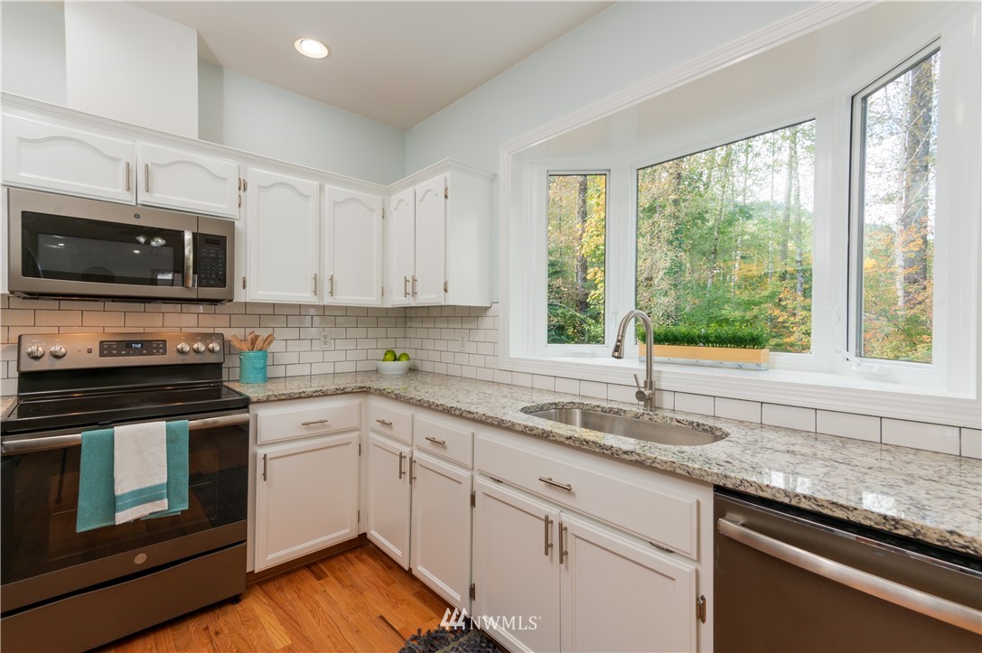 1220 Southwest 12th Street North Bend, WA 98045 - Photo 7 of 25 a kitchen with granite countertop a sink cabinets stainless steel appliances and a window