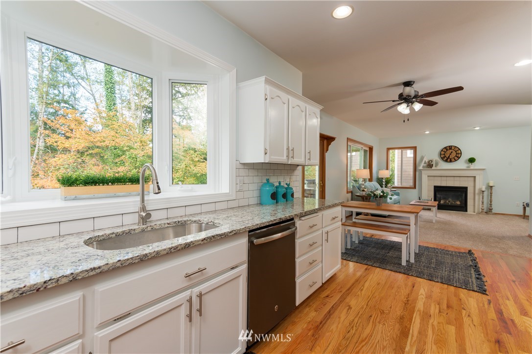 1220 Southwest 12th Street North Bend, WA 98045 - Photo 8 of 25 a large kitchen with granite countertop a stove a sink dishwasher and a fireplace with wooden floor