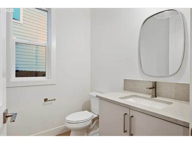 a bathroom with a toilet a sink a mirror and a window