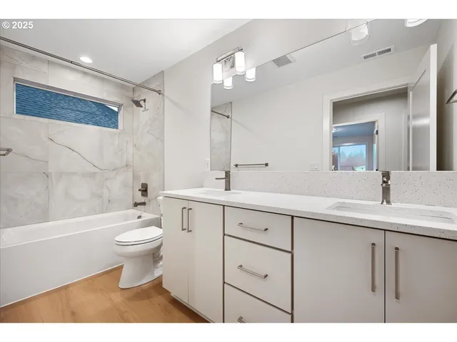 a bathroom with a toilet a sink a mirror a bathtub and shower