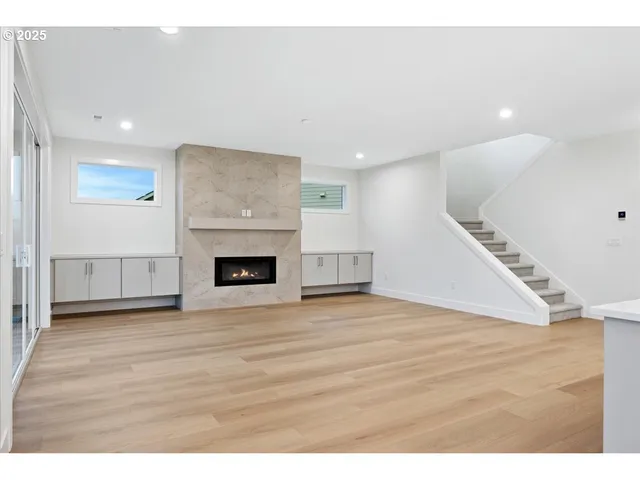 a view of an empty room with wooden floor fireplace and a window