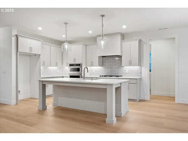 a kitchen with kitchen island granite countertop a sink cabinets and stainless steel appliances