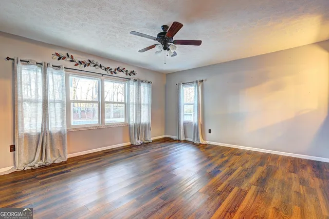 an empty room with wooden floor and windows