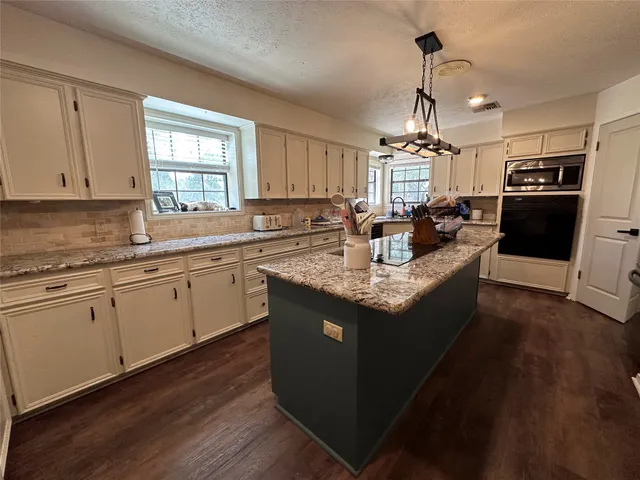 a kitchen with kitchen island granite countertop a sink cabinets and stainless steel appliances