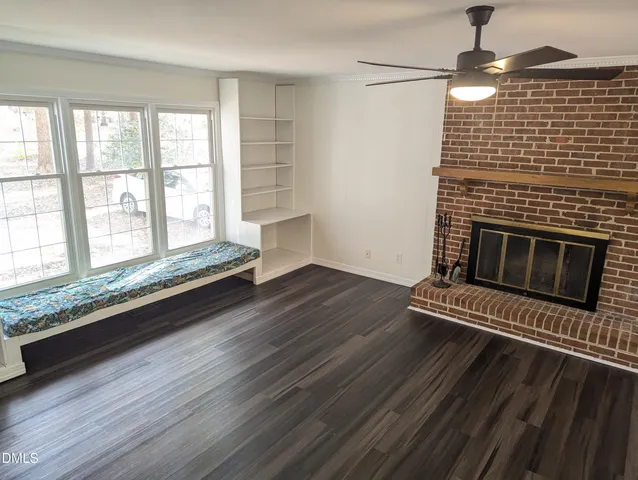 a view of wooden floor fire place and windows in an empty room