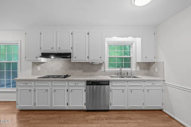 a kitchen with stainless steel appliances granite countertop a sink a stove and white cabinets