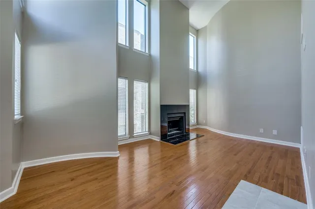 an empty room with wooden floor fireplace and windows