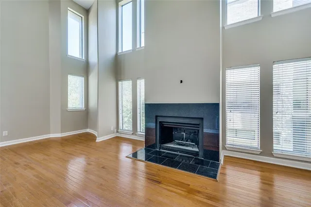 a view of an empty room with wooden floor fireplace and a window