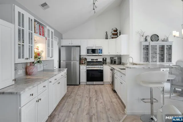 a kitchen with granite countertop a sink stainless steel appliances and cabinets