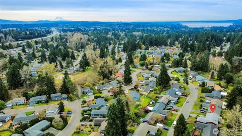 an aerial view of residential house with parking and trees