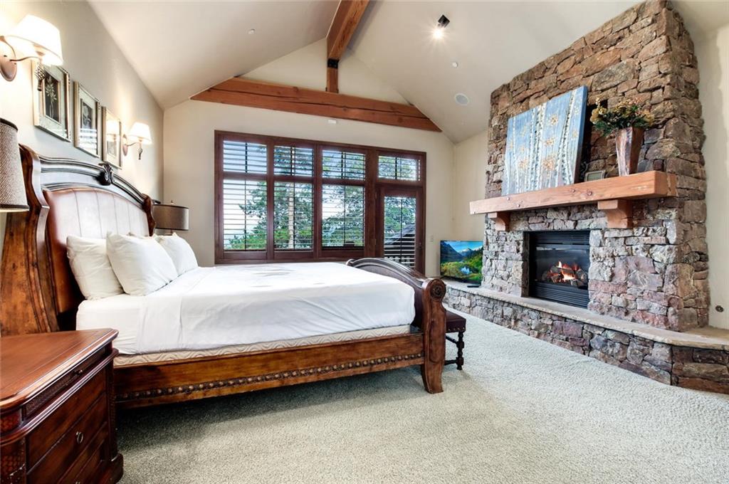 1050 4 O Clock Road Breckenridge, CO 80424 - Photo 17 of 35 a spacious bedroom with a bed a fireplace and a large window